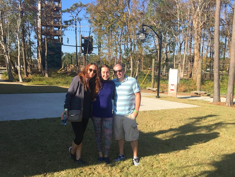 Michelle Della Giovanna from Full Time Explorer stands with her sister and brother-in-law stand in front of an Aerial Ropes Course in Myrtle Beach