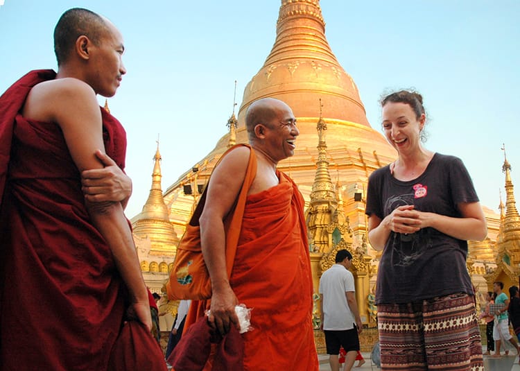 Michelle Della Giovanna from Full Time Explorer laughs while talking to monks in front of Shwedagon Pagoda in Myanmar