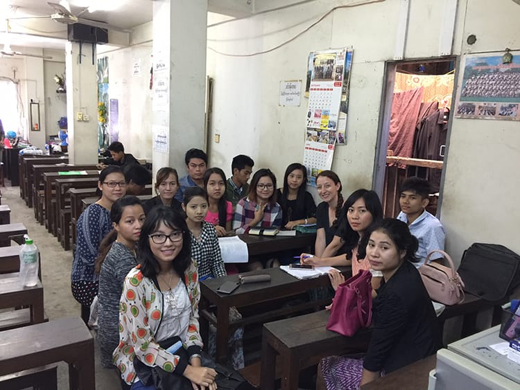 Michelle Della Giovanna from Full Time Explorer sits with students in an English class in Yangon, Myanmar