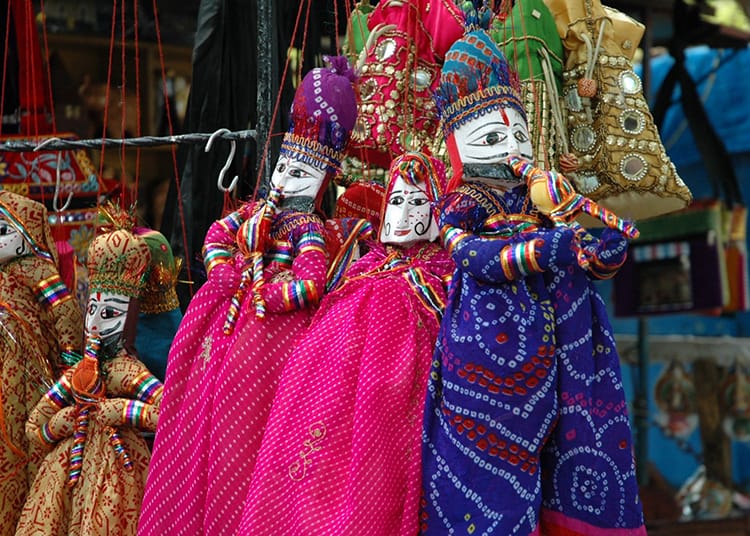 Colorful handmade puppets that are for sale hang on display at a vendors booth