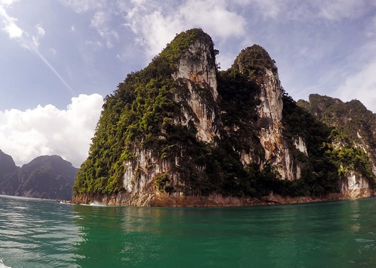 Large limestone mountains stick out of the water in Khao Sok National Park