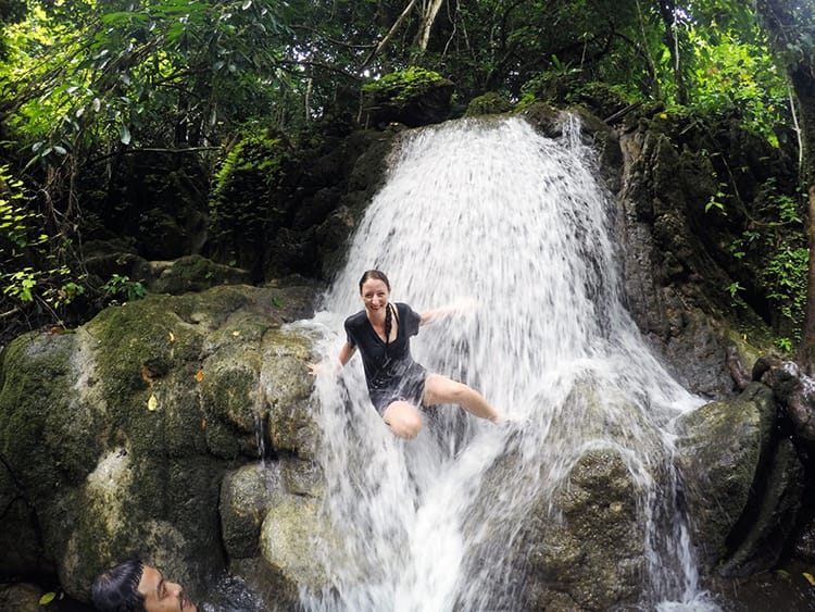 Michelle Della Giovanna from Full Time Explorer laughs as she slips and slides while climbing across a small waterfall