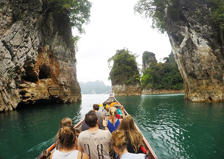 A long boat takes a group of tourists into Khao Sok National Park and through the large limestone rock formations sticking out of the water