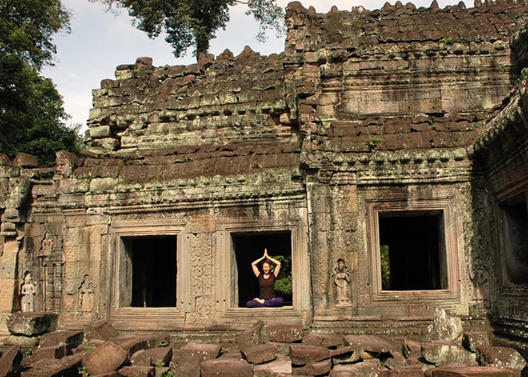 Michelle Della Giovanna from Full Time Explorer sits in the window of one of the stone temples in Angkor Wat