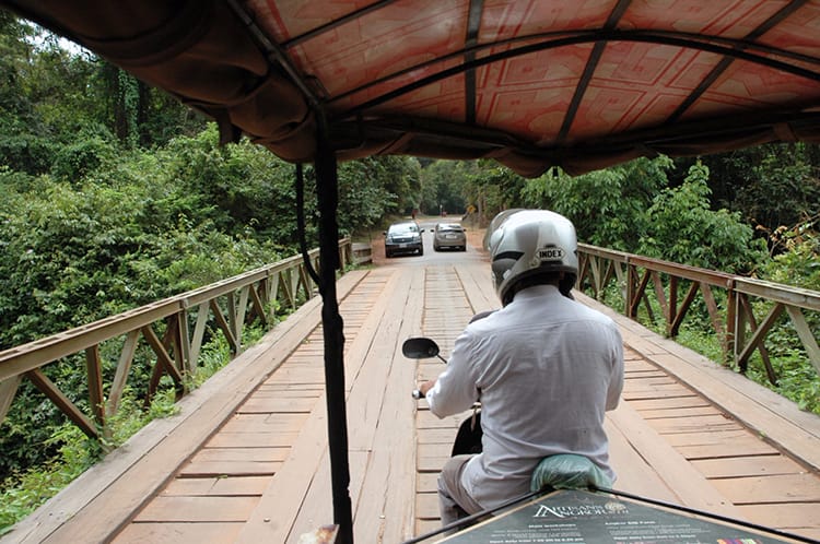 A tuk-tuk drives over a wooden bridge on the way to a temple at Angkor Wat