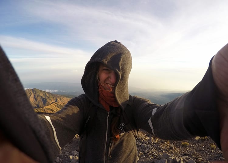 Michelle Della Giovanna from Full Time Explorer tries to take a selfie at the Mt Rinjani summit but it's super windy and her hood blows in her face