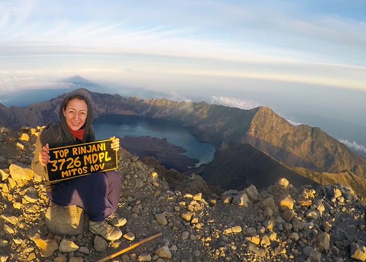 Michelle Della Giovanna from Full Time Explorer holds the summit sign for Mt. Rinjani after making it to the top
