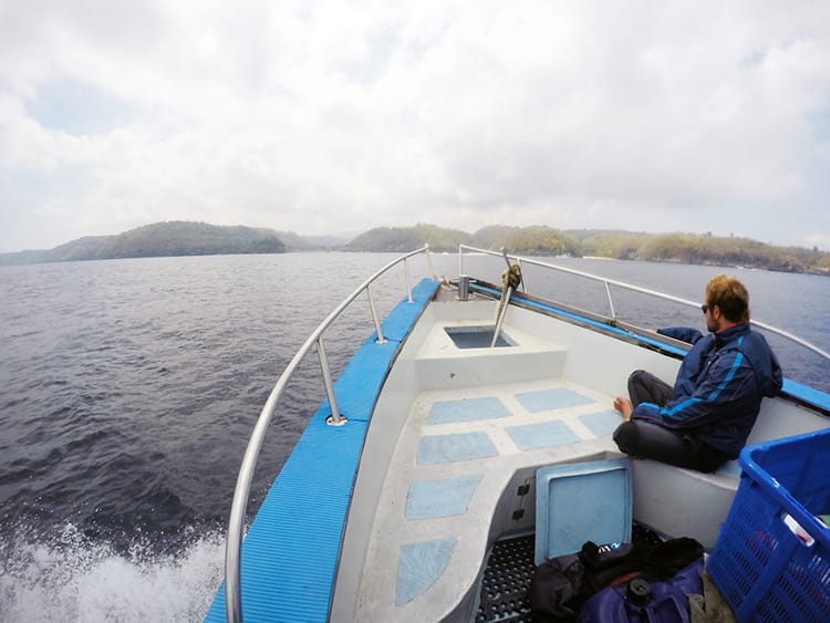 A man sits on the front of a boat as it heads out to a dive