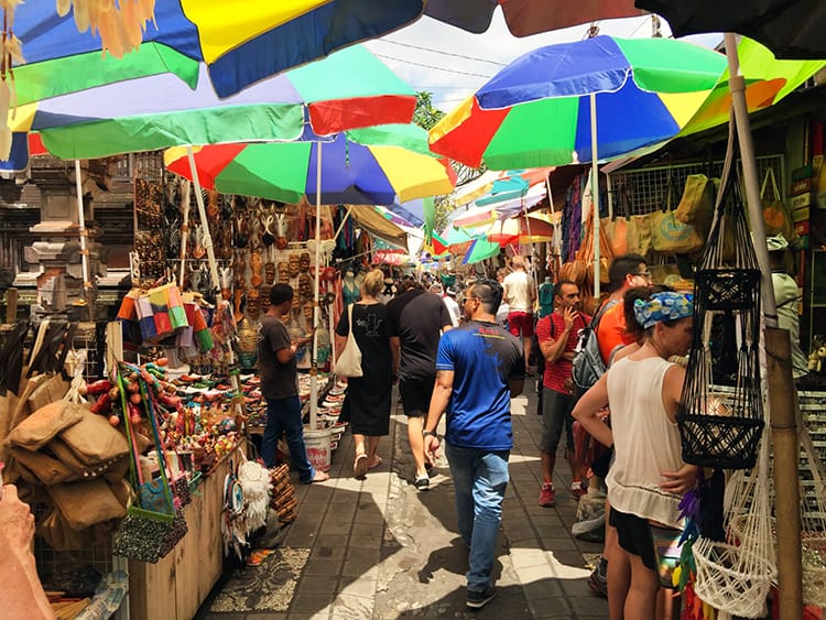 A street in Ubud, Bali lined with stands and brightly colored umbrellas selling trinkets to tourists