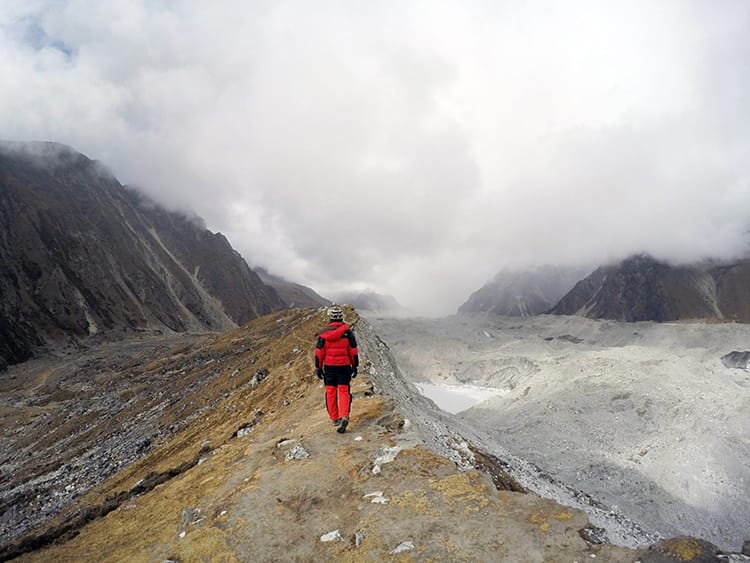 Michelle Della Giovanna from Full Time Explorer walks on the glacier rim with Gokyo on her left and the glacier on her right