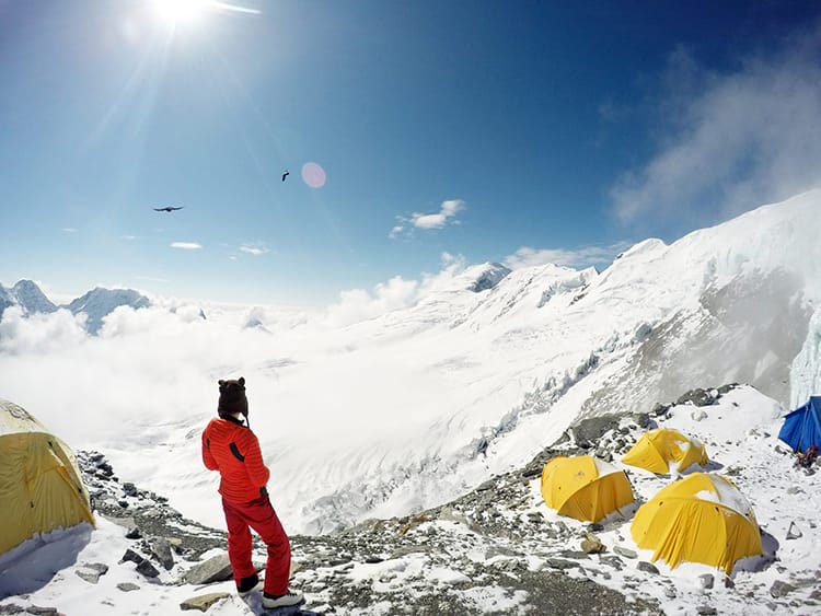 Michelle Della Giovanna from Full Time Explorer stands in high camp looking out at the view of the Everest Region above the clouds