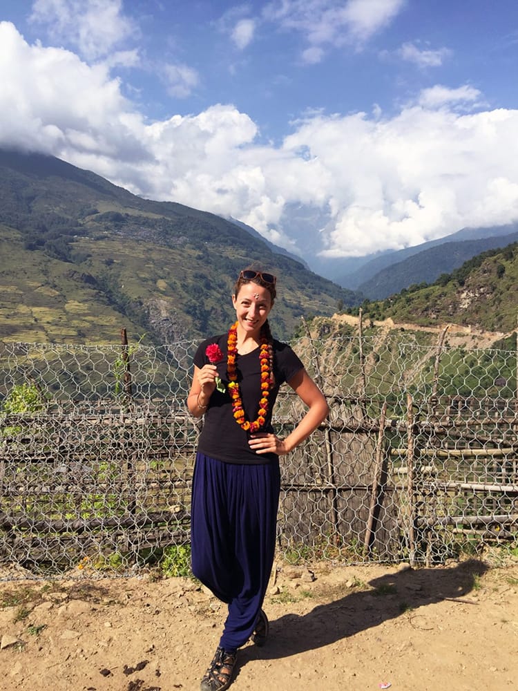 Michelle Della Giovanna from Full Time Explorer wearing a modest t-shirt and baggy pants in a small village in Nepal
