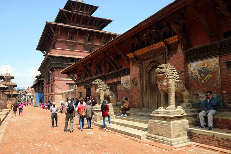 Tourists walk through Patan Durbar Square admiring the wood carvings