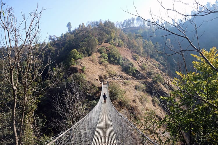 A trekker crosses a suspension bridge between Balthali and Panauti