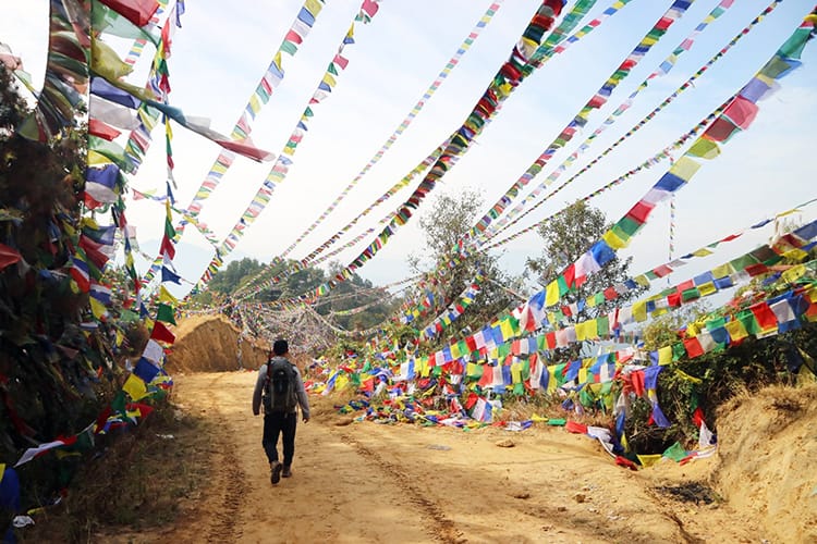 A trekkers walks through prayer flags near Namo Buddha Monastery in Nepal