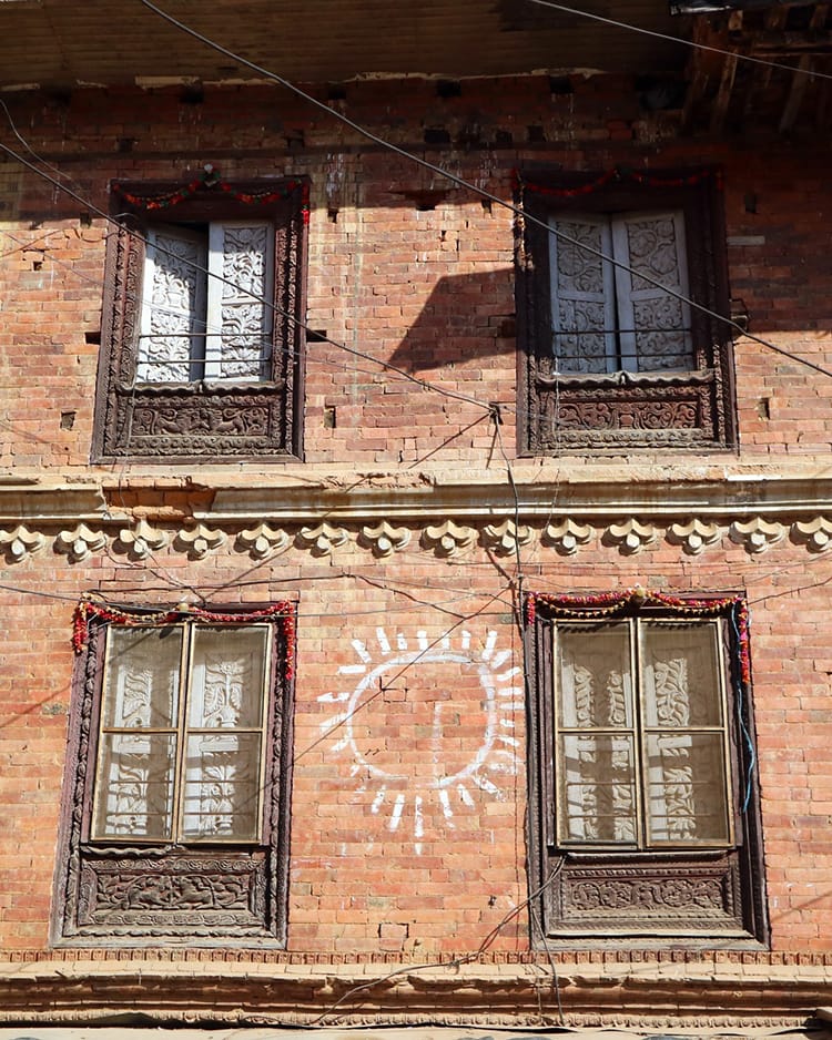 A sun drawn on the side of an old brick building in Panauti Nepal