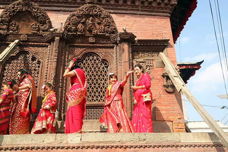 Girls walk around a temple in Kathmandu Durbar Square while waving to family below
