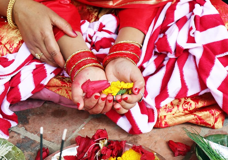 A young Nepali girl holds flowers in her hands during the Ehee puja