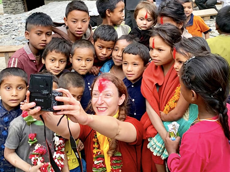 Michelle Della Giovanna from Full Time Explorer takes a selfie with a group of children in Kaina Bazaar