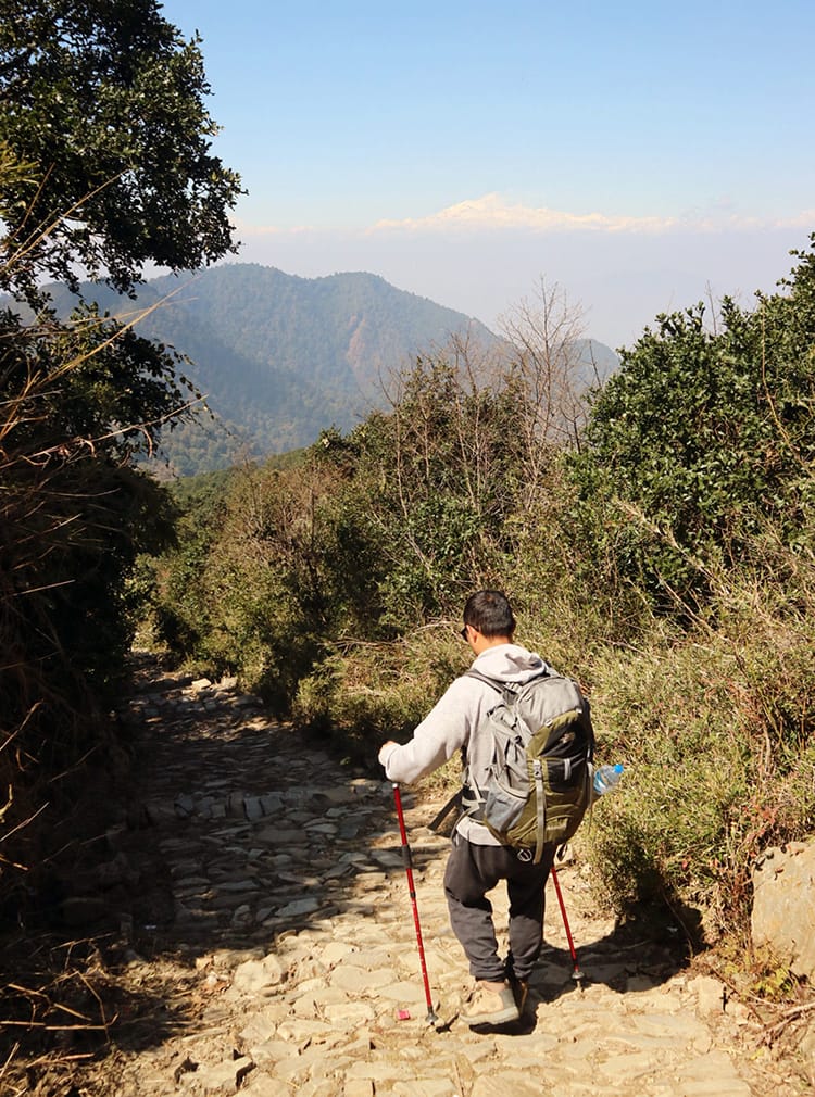 Suraj walks downhill with the mountains in the distance