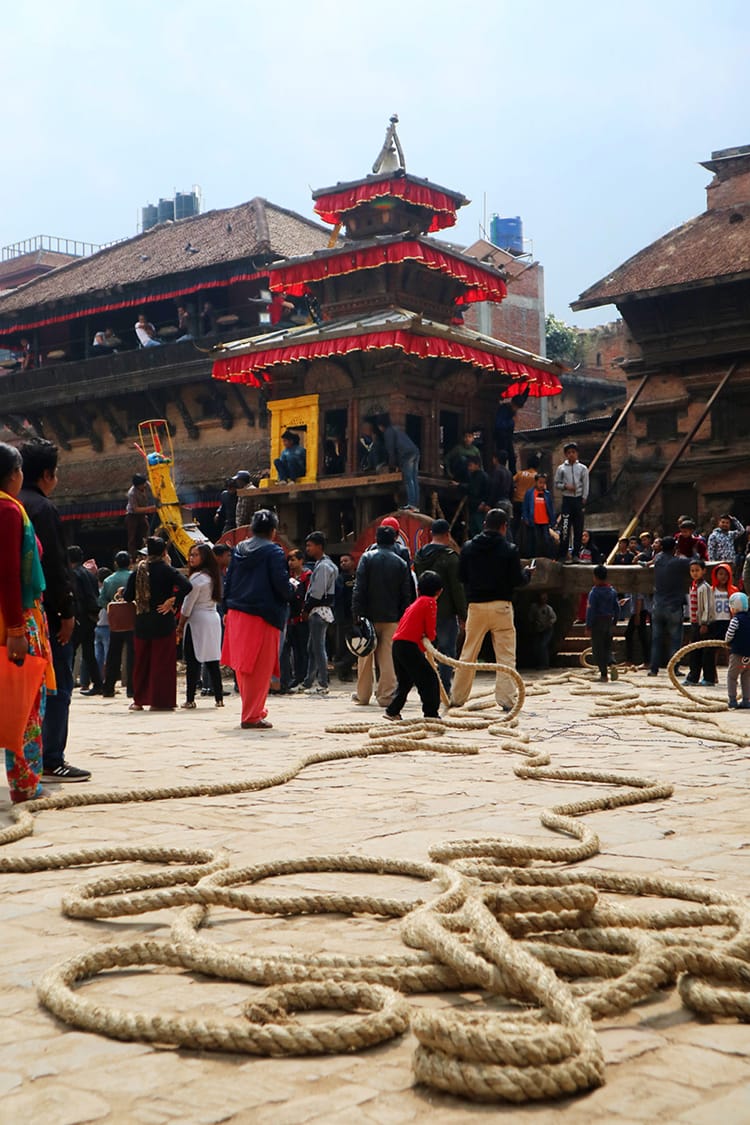 A large rope lays on the floor while a little kid pretends to pull the chariot
