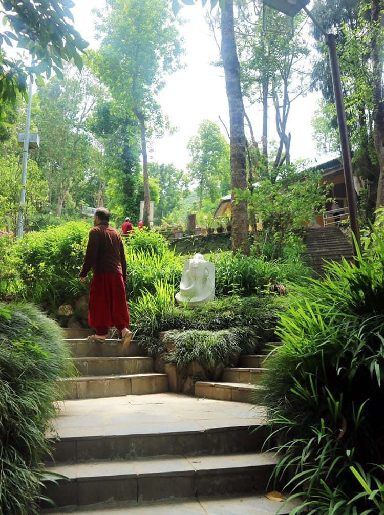 A man wears a maroon robe while walking to the meditation hall