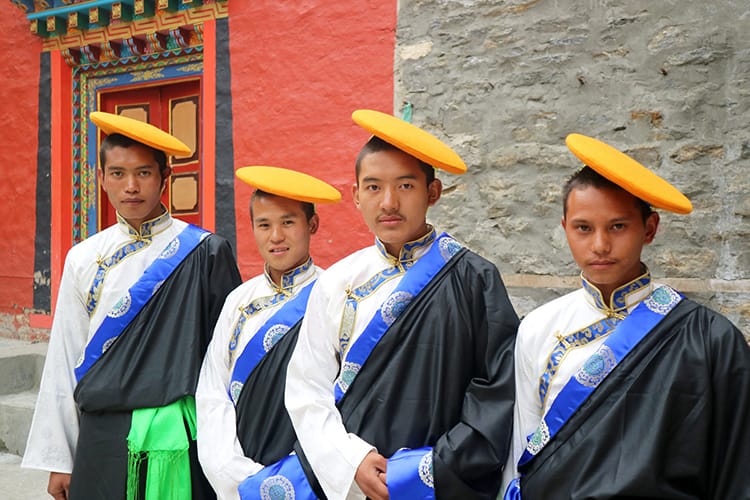 Four Nepali men dressed in traditional Sherpa clothing get ready to perform a traditional dance for visitors