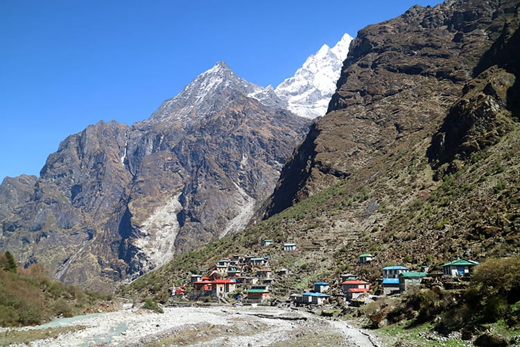 The little village of Beding, Nepal seen from afar with the Himalaya mountains overhead