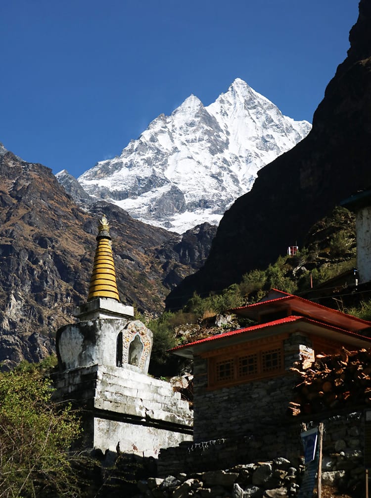 The bright white Himalaya mountains tower over a small Buddhist Stupa below