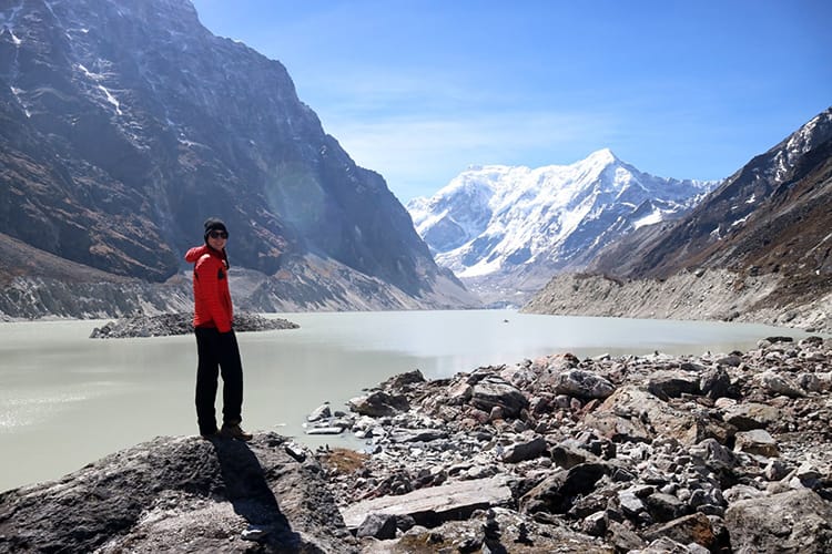 Michelle Della Giovanna from Full Time Explorer stands looking out over the light green waters of Tsho Rolpa Lake