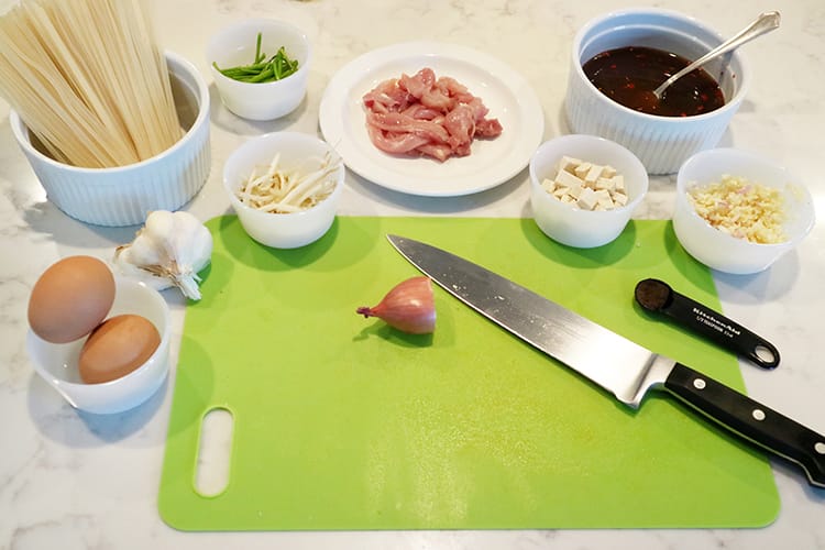 Fresh ingredients used to make peanut free Pad Thai being prepped on a cutting board