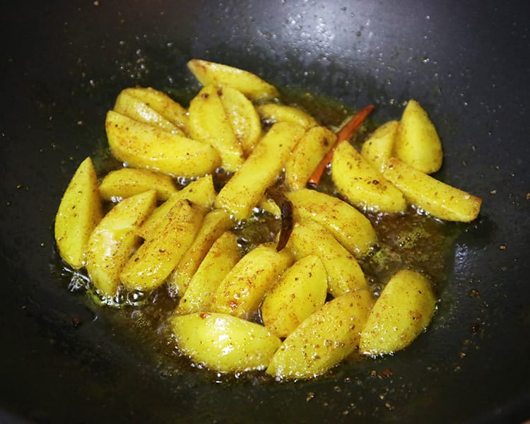 Potatoes cooking in a fry pan with salt and turmeric
