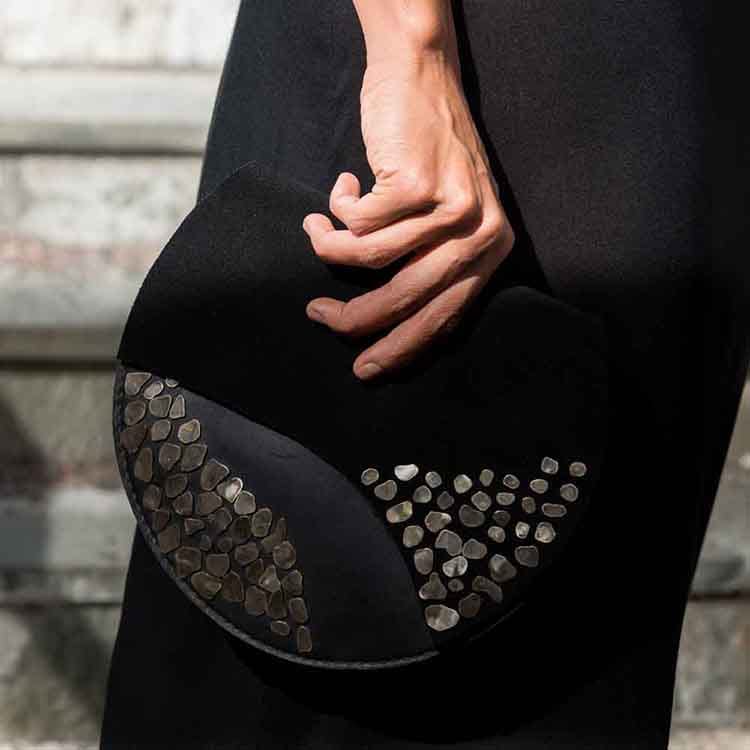A women carries a black purse with metal work on the side