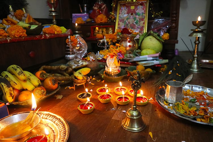 Candles, fruits, money, and other offerings are laid out on the floor for the goddess Laxmi