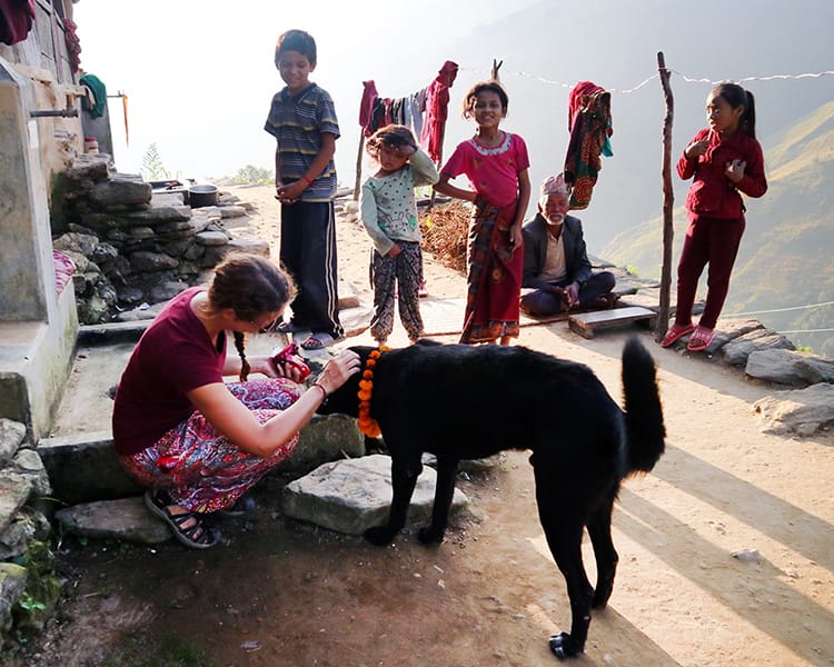 Michelle Della Giovanna from Full Time Explorer puts a marigold mala on a village dog in Tangting, Nepal