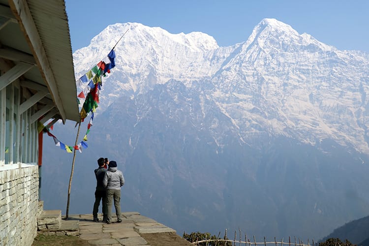 Two trekkers take pictures in front of the massive Annapurna Range at Mardi Himal High Camp