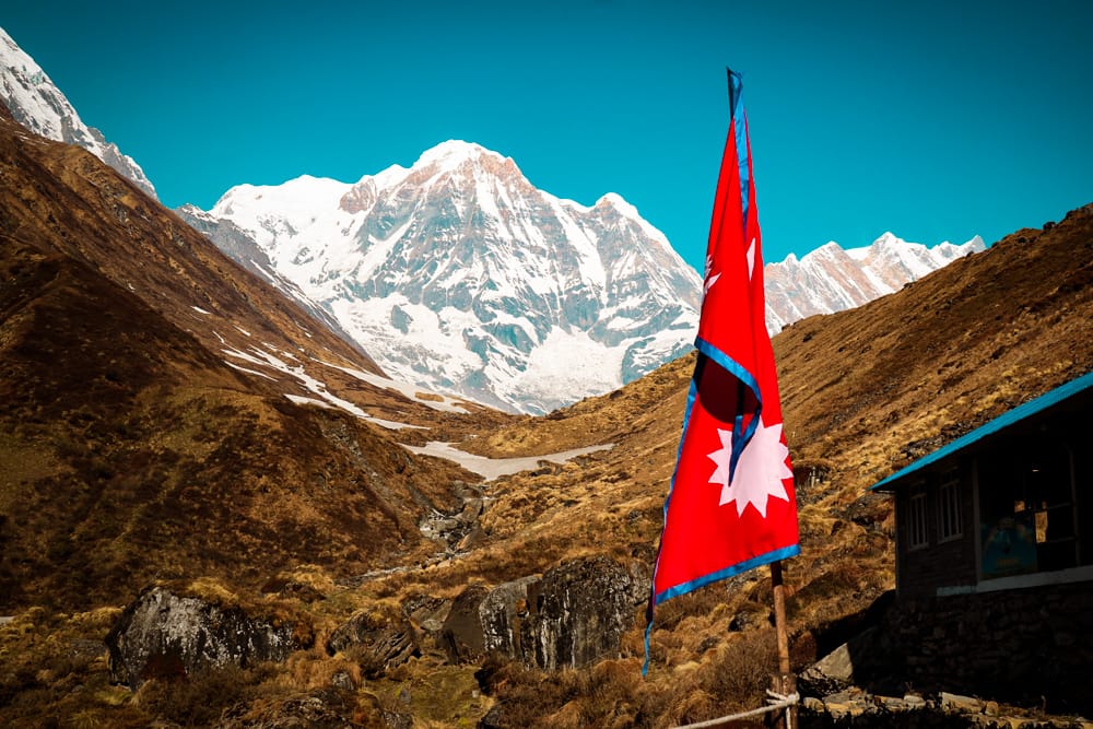 A Nepali flag stands in front of the mountains as seen from MBC