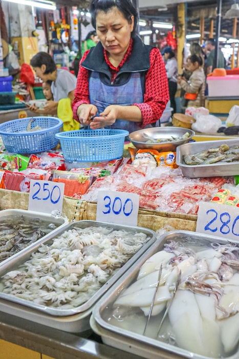 A woman prepares seafood in a morning market in Chiang Mai