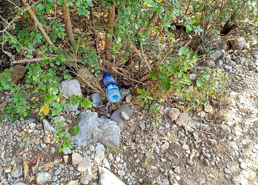 a plastic water bottle dumped along a trekking trail