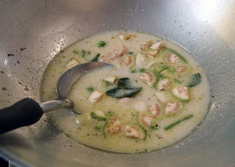 Thai green curry with chicken being cooked on a stove