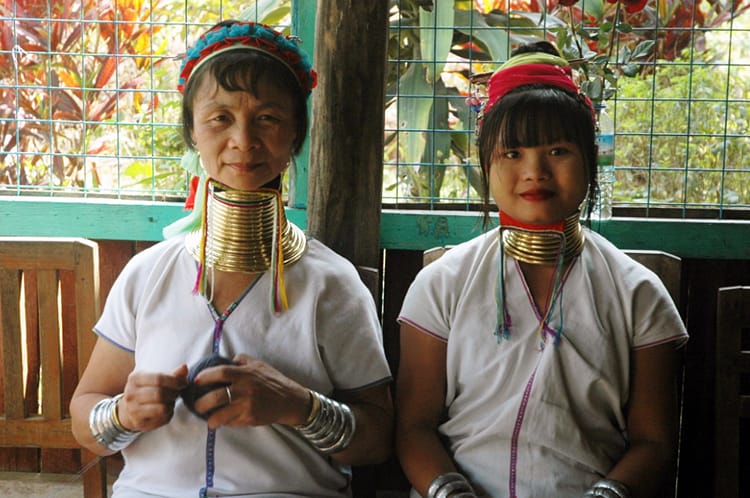 Two woman wear gold rings around their neck and pose for photos