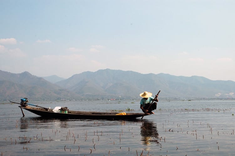 A fisherman sits at the front of his boat in Inle Lake, Myanmar