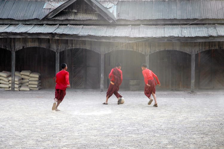 Three novice monks play soccer in front of a monastery in Myanmar