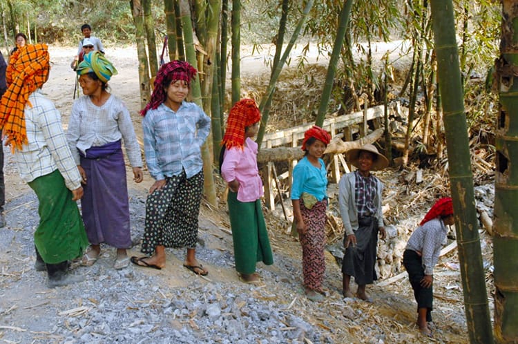 Burmese women wearing colorful clothes help build a dam on the Kalaw Trekking route
