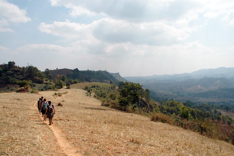 Hikers walk on a dirt path through the hills of Myanmar on the Kalaw Trek to Inle Lake