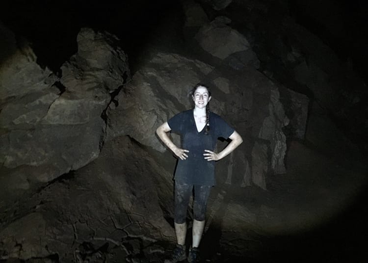 Michelle Della Giovanna from Full Time Explorer stands in a cave in Thailand covered in dirt