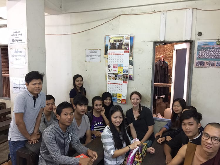 Michelle Della Giovanna from Full Time Explorer sits with students in an English class in Yangon, Myanmar