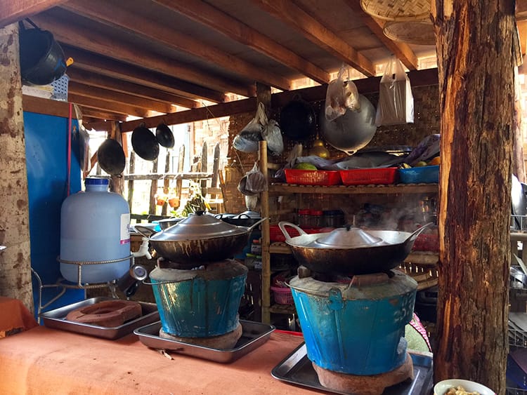 The outdoor kitchen for our Burmese cooking class in Inle Lake which has large metal pots cooking on coal