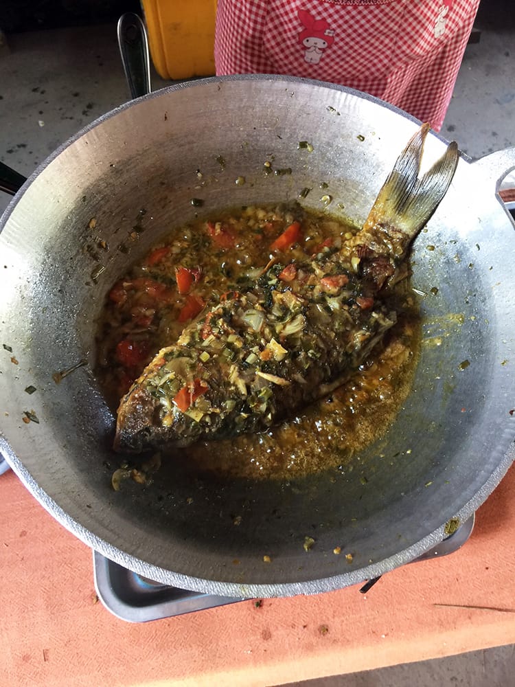 The Burmese fish curry cooking on the stove in a large metal pan