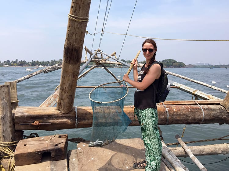 Michelle Della Giovanna from Full Time Explorer holds a net full of small fish at the Chinese fishing nets in Kochi